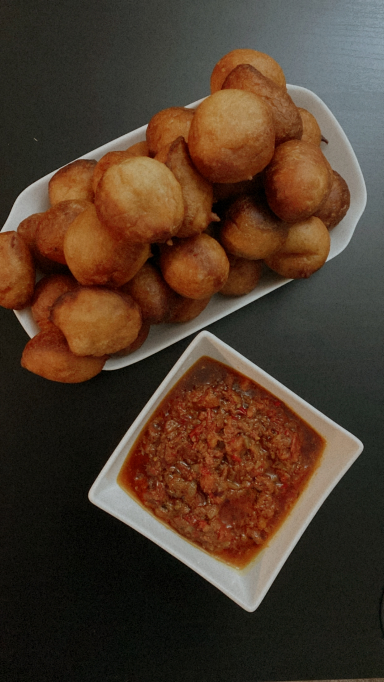 Heap of puff puff with pepper sauce.