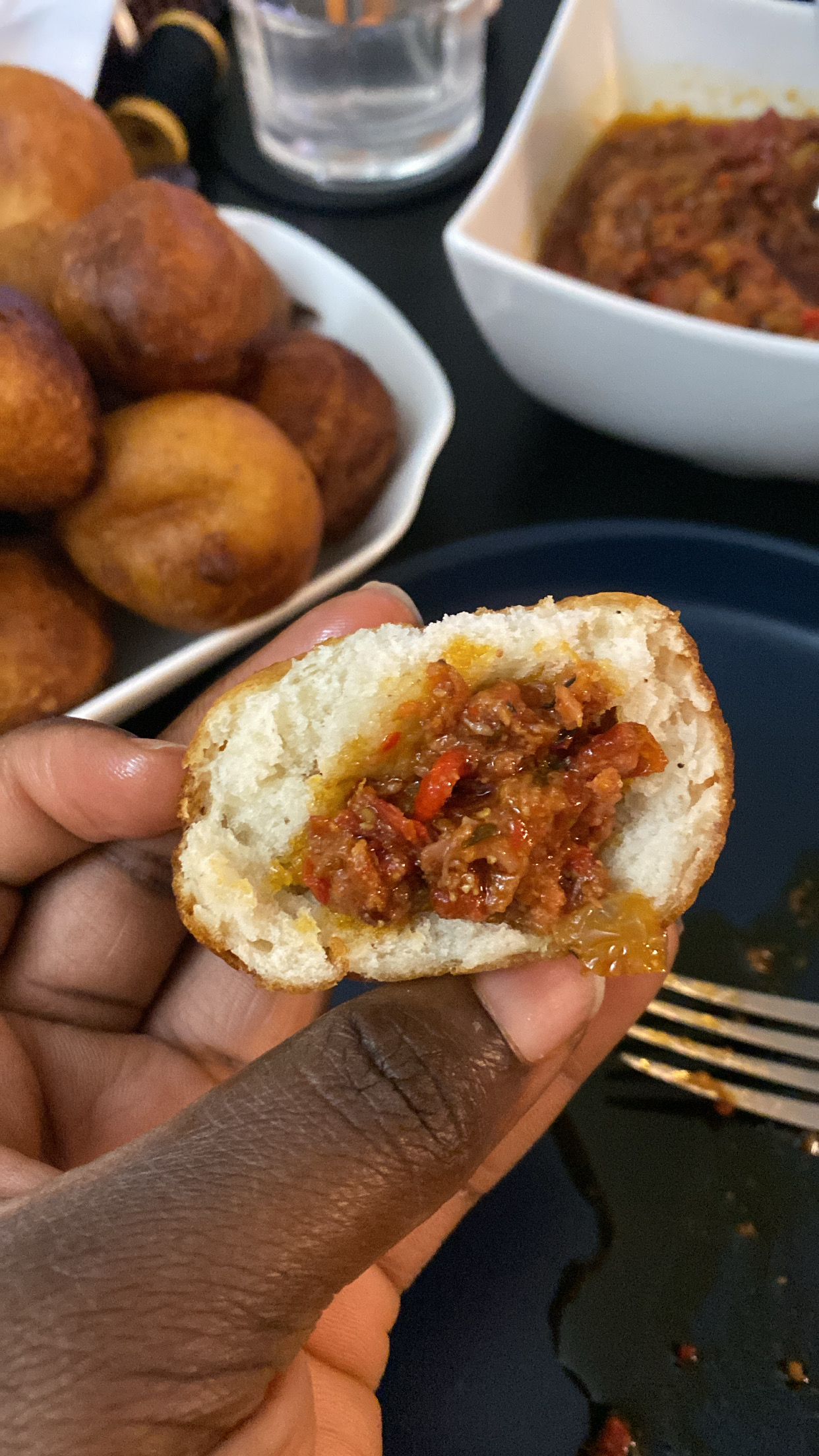 Puff Puff cut in half with a scoop of pepper sauce.